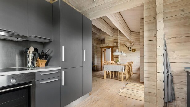 A modern kitchen with grey cabinets, a built-in oven, and a dining area with a wooden table and chairs. - Beautiful home in Hemmet with kitchen (Hemmet)