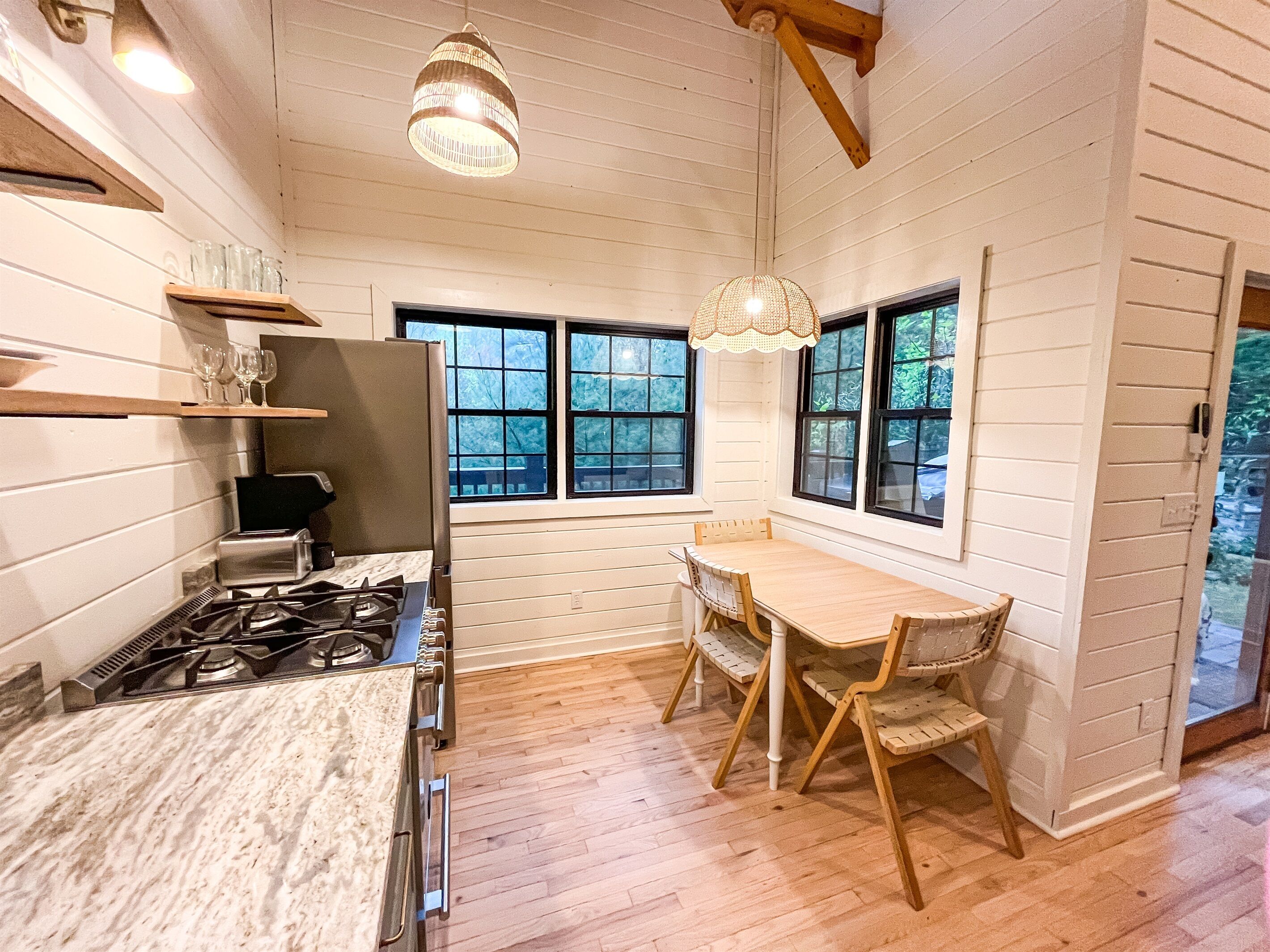 Une cuisine de taille réduite, équipée d’une cuisinière à gaz, de meubles en bois et d’une table à manger avec des chaises.