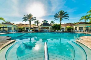 A clear view of a swimming pool with lounge chairs and palm trees, surrounded by buildings with a central dome structure. - 6 Bedroom Luxury Pool Villa close to Disney Private Nature Preserve (Kissimmee)