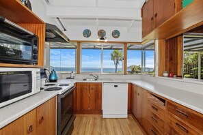 A kitchen with wooden cabinets, a microwave, a stove, and a dishwasher. - Hannah's Bay Lakefront - Kayaks, Sleeps 8 (Rotorua)