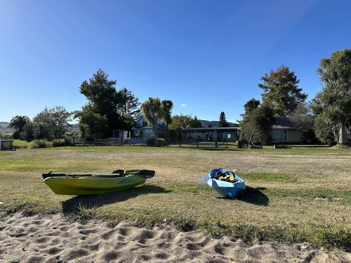 A grassy field with a yellow kayak and a blue container with items.