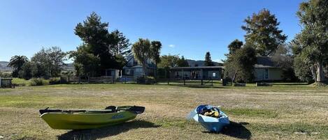 A grassy field with a yellow kayak and a blue container with items.