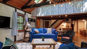 Un salon chaleureux avec un canapé bleu, une table basse en bois et un coin repas agrémenté d’une chaise en osier.