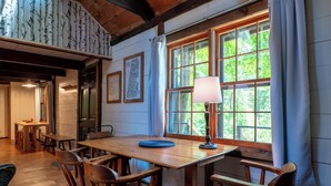 Une table à manger en bois, avec des chaises, une lampe et une fenêtre avec des rideaux.