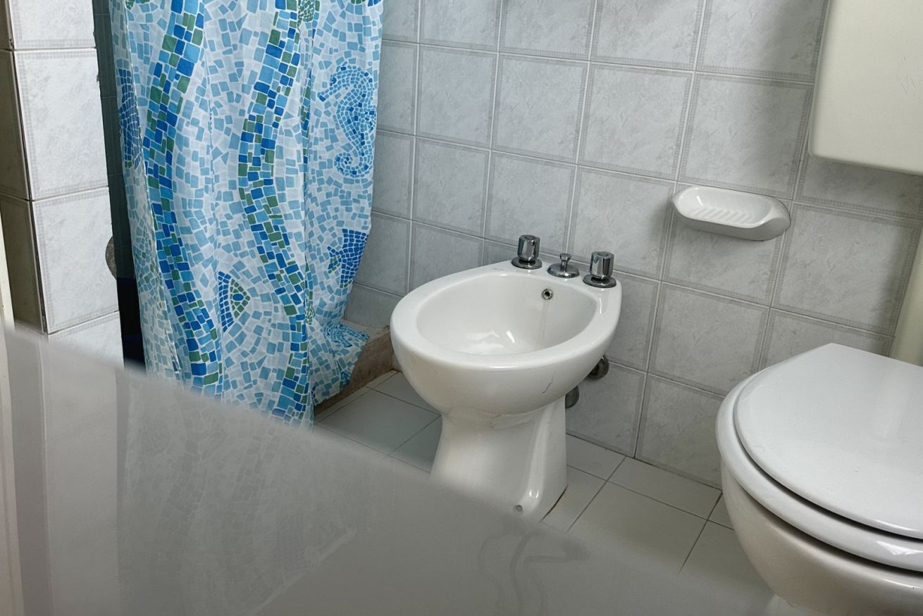 A bathroom with a bidet, a toilet, and a tiled floor.