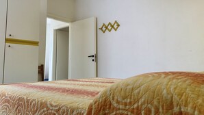 A bedroom with a bed, a wardrobe, and an open door leading to another room. - F002 - Fano, three-room apartment with porch 30m from the sea (Fano)