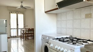 Eine Küche mit Gasherd, Waschmaschine und Deckenventilator.