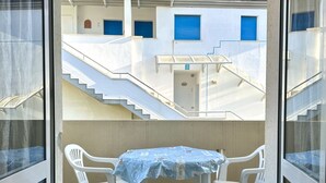 Ein Balkon mit Tisch und Stühlen, eine Treppe und ein Gebäude mit blauen Fensterläden.