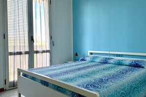 A bedroom with a bed, a nightstand, a lamp, and a window with blinds.