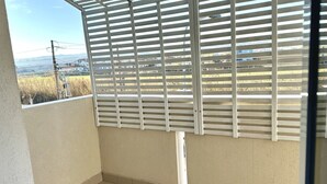 Un balcón con vistas a un paisaje urbano, barandilla blanca y piso de baldosas.