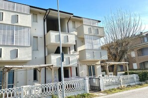 A multi-story residential building with balconies, a gated entrance, and a clear sky. - F006 - Fano, three-room apartment with small terrace 30m from the sea (Fano)