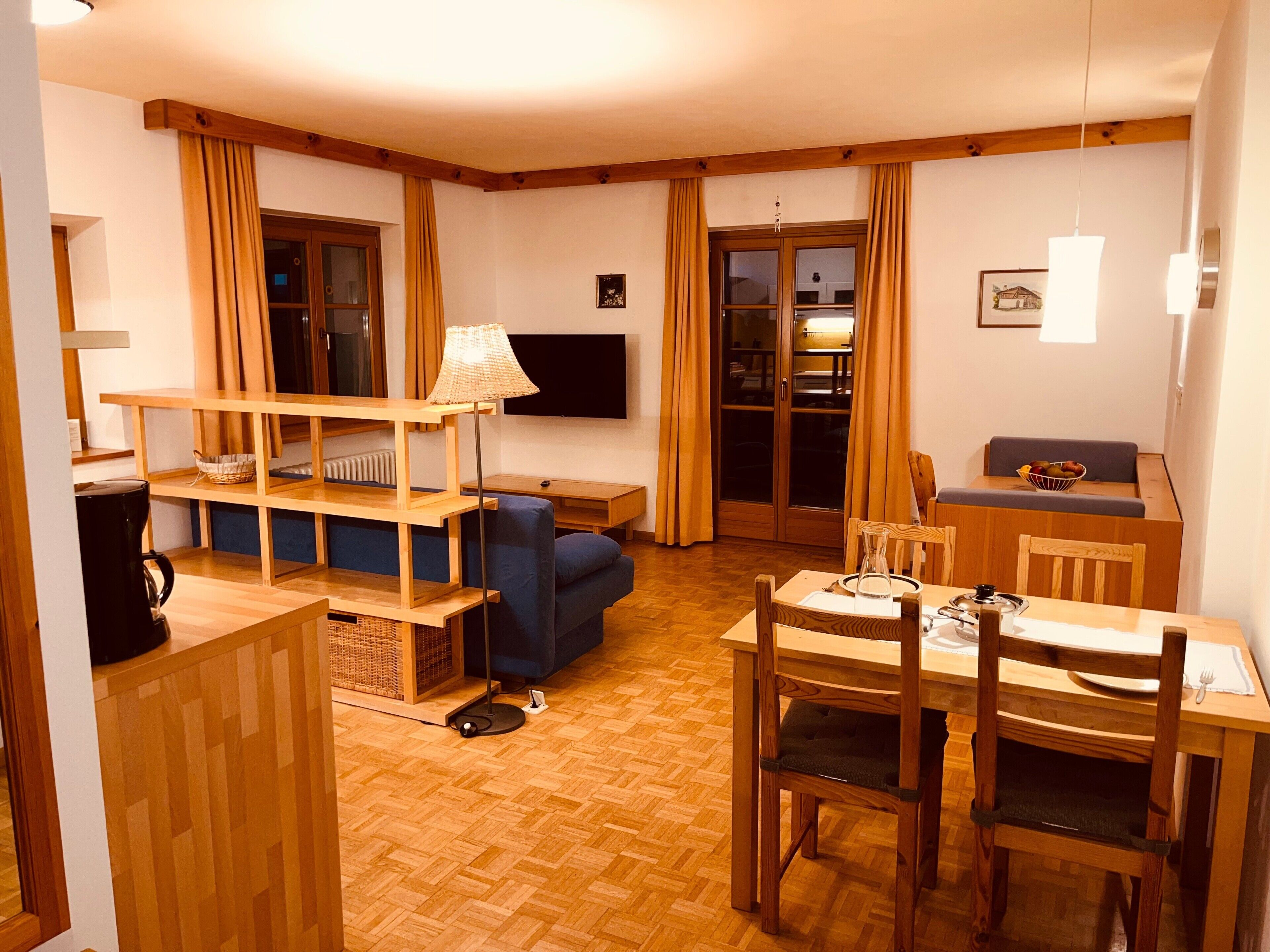Un espace de vie compact comprenant un coin repas, un canapé, une table basse et un téléviseur.