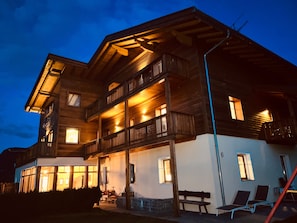 Un bâtiment en bois à plusieurs étages, doté de balcons et de grandes fenêtres, qui ressemble probablement à un hôtel ou à un chalet.
