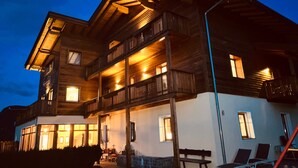Een meerhoog gebouw van hout, met balkons, grote ramen en een veranda.