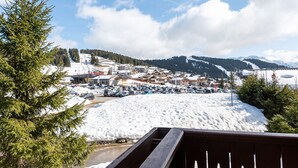 A snowy mountain town with buildings, a parking lot, and a clear sky. - Apartment 'Lapon H10' with Mountain View and Balcony (Hauteluce)