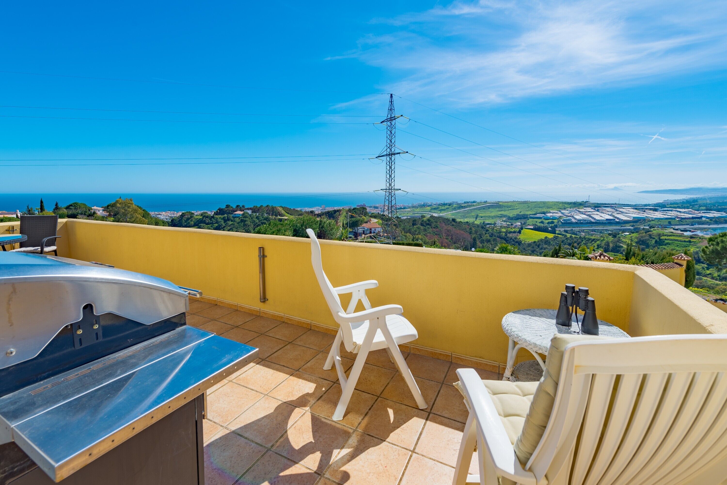 A balcony with a view of the sea, a power line, and a tiled floor.