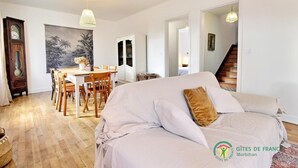A spacious room with a large bed, a dining area with wooden furniture, and a staircase leading to another level. - Fleur D'ajonc - Locoal Mendon (LOCOAL MENDON)