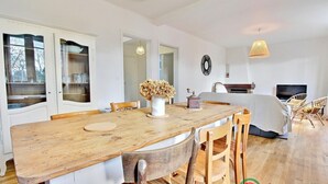 A spacious living area with a wooden dining table, chairs, a sofa, and a television. - Fleur D'ajonc - Locoal Mendon (LOCOAL MENDON)