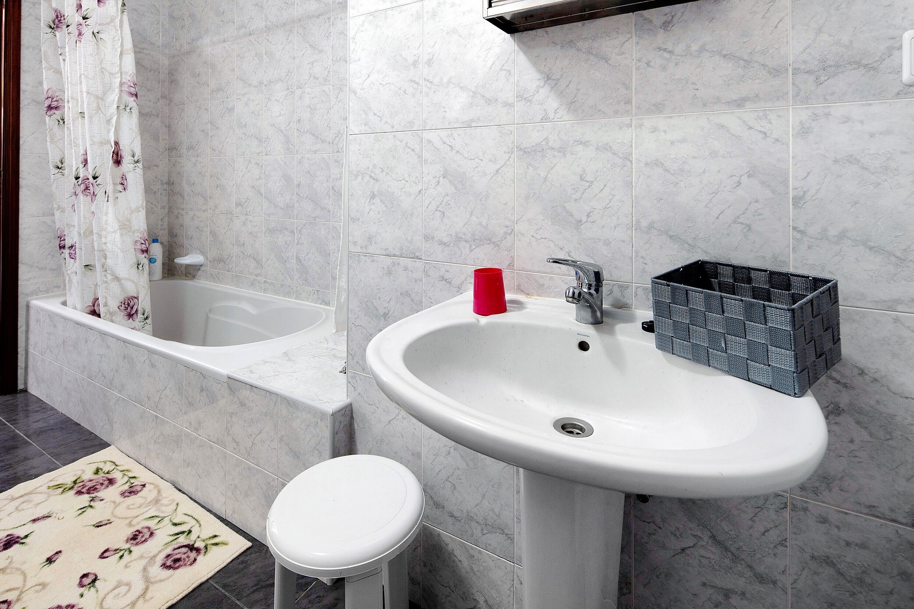 Une salle de bain équipée d’une baignoire, d’un lavabo, de toilettes et d’un rideau de douche.