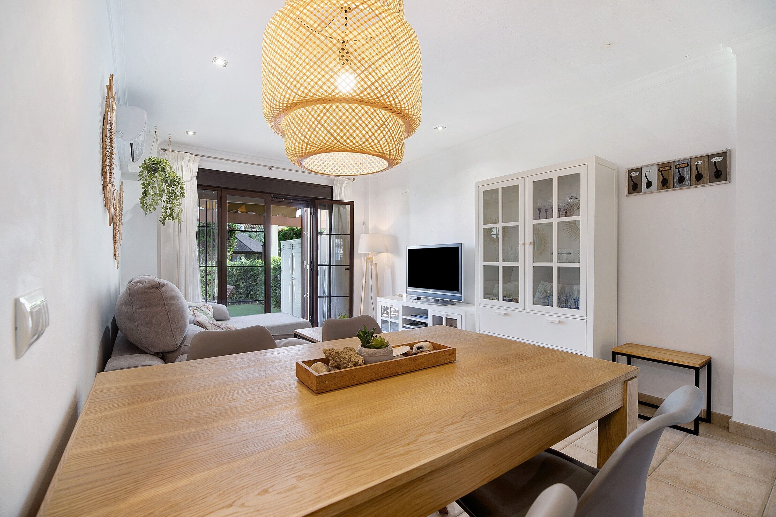 A modern dining area with a wooden table, a television, and a white cabinet.