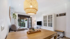 A modern dining area with a wooden table, a television, and a white cabinet.