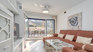 Un salon moderne avec un canapé, une table basse en verre et une porte-fenêtre coulissante donnant sur une terrasse extérieure.