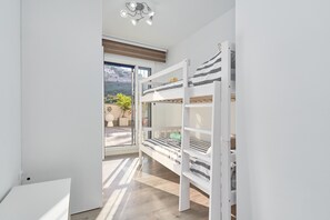 Et værelse med køjeseng, stort vindue og udsigt til en bakke.