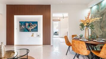A modern dining area with a round table, orange chairs, and a vase of flowers.