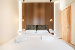 A modern hotel room with a large bed, wooden headboard, two bedside tables, and a wooden wardrobe.