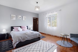 A bedroom with a bed, bedside tables, a window with curtains, a chair, and a rug.