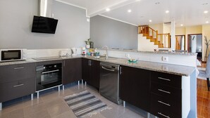 Eine moderne Küche mit integrierten Geräten, darunter Mikrowelle, Backofen und Geschirrspüler, sowie eine Treppe, die in eine weitere Ebene führt.