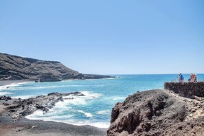 A coastal landscape with rocky terrain and a clear blue sea.