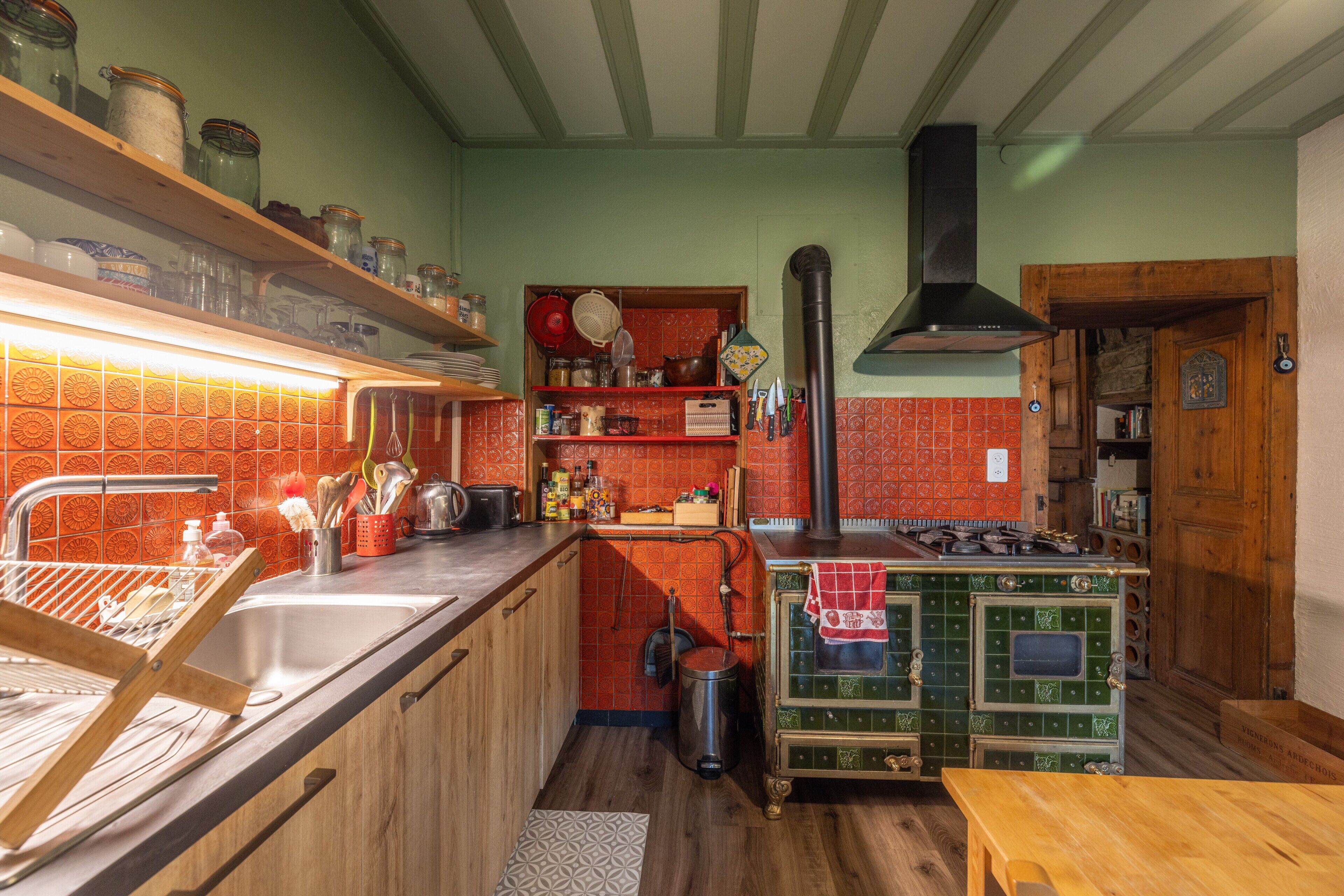 Une cuisine équipée d’une cuisinière, d’un évier et d’étagères remplies de bocaux.