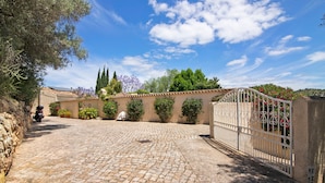 A cobblestone driveway leading to a gated entrance with a stone wall on one side and a tree on the other. - Holiday Home 'Casa Felix Number 2' with Shared Pool, Shared Terrace and Wi-Fi (Loulé)