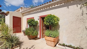 A building with a tiled patio, potted plants, and a red door. - Holiday Home 'Casa Felix Number 2' with Shared Pool, Shared Terrace and Wi-Fi (Loulé)