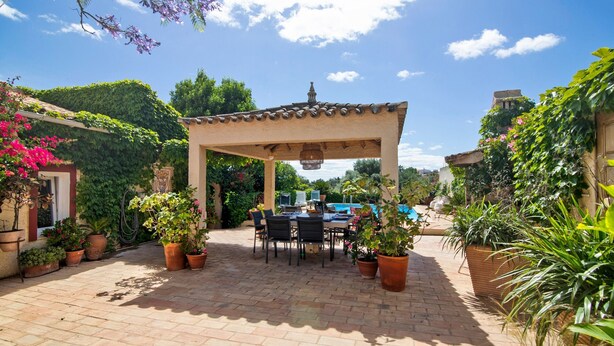 A patio with a pergola, potted plants, and a table with chairs. - Villa 'Casa Felix' with Private Pool, Private Terrace and Wi-Fi (Loulé)