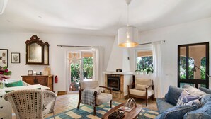 A living room with a fireplace, a dining area with a table and chairs, and a large window with curtains. - Villa 'Casa Felix' with Private Pool, Private Terrace and Wi-Fi (Loulé)
