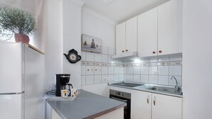 A kitchen with white cabinets, a stainless steel refrigerator, a coffee maker, and a sink.