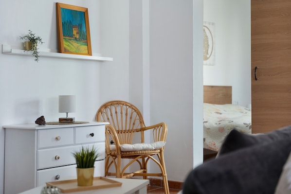 A bedroom with a bed, a chair, a dresser, and a painting on the wall.
