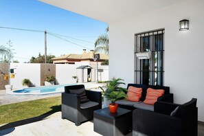 An outdoor patio with a pool, a sofa set, and a potted plant.