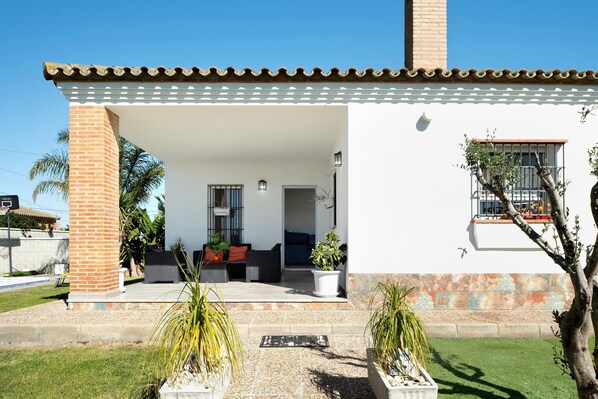 Uma casa com varanda coberta, chaminé de tijolos e janela com varanda.
