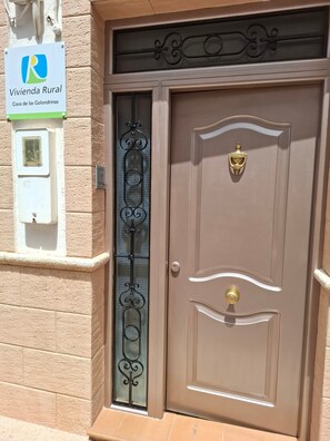 A brown door with a brass knocker and a glass panel with a metal design.