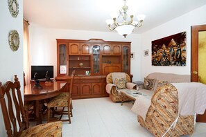 A dining area with a wooden table and chairs, a television, and a cabinet with glass doors.