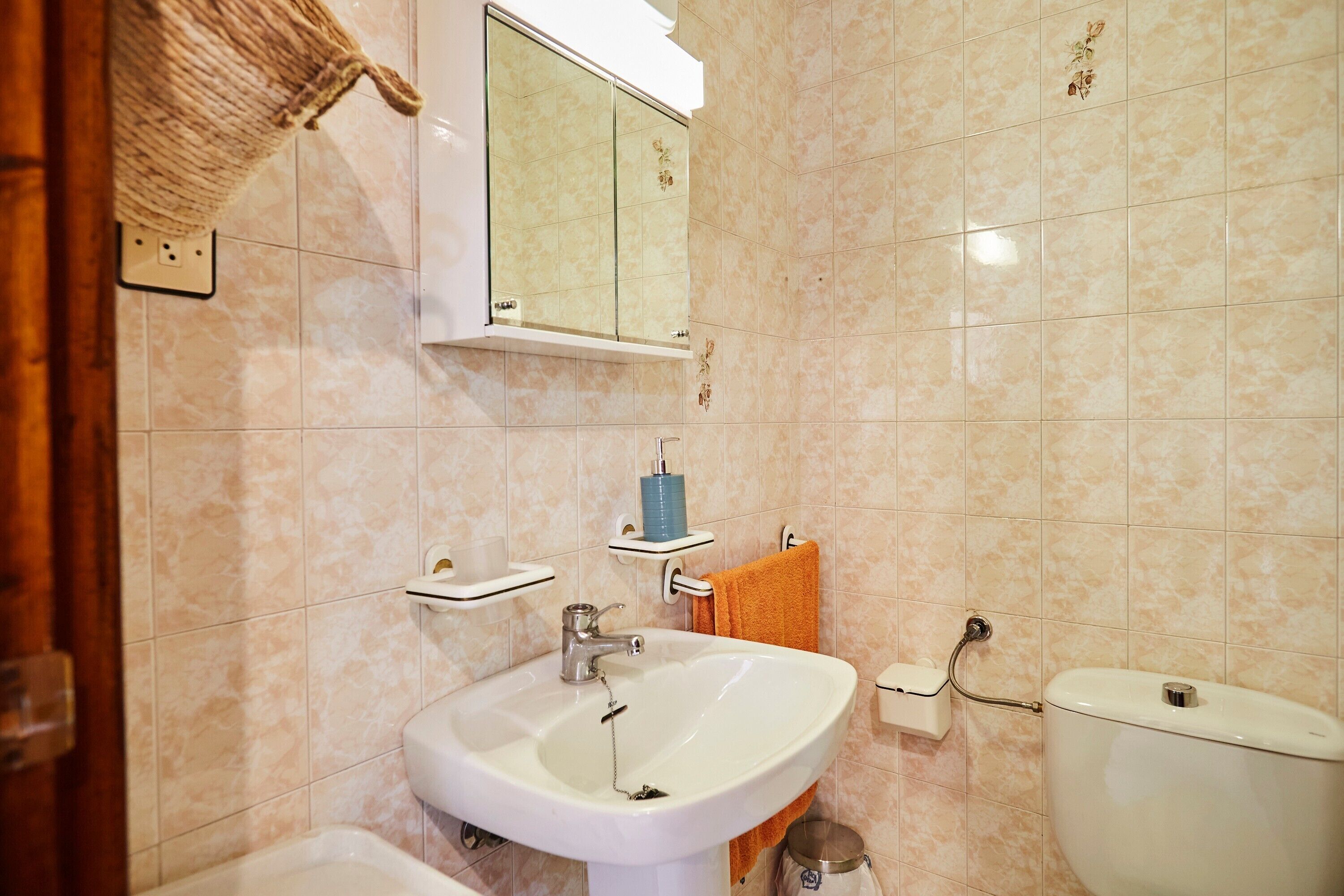 Un bagno con lavandino, specchio, water e porta asciugamani.