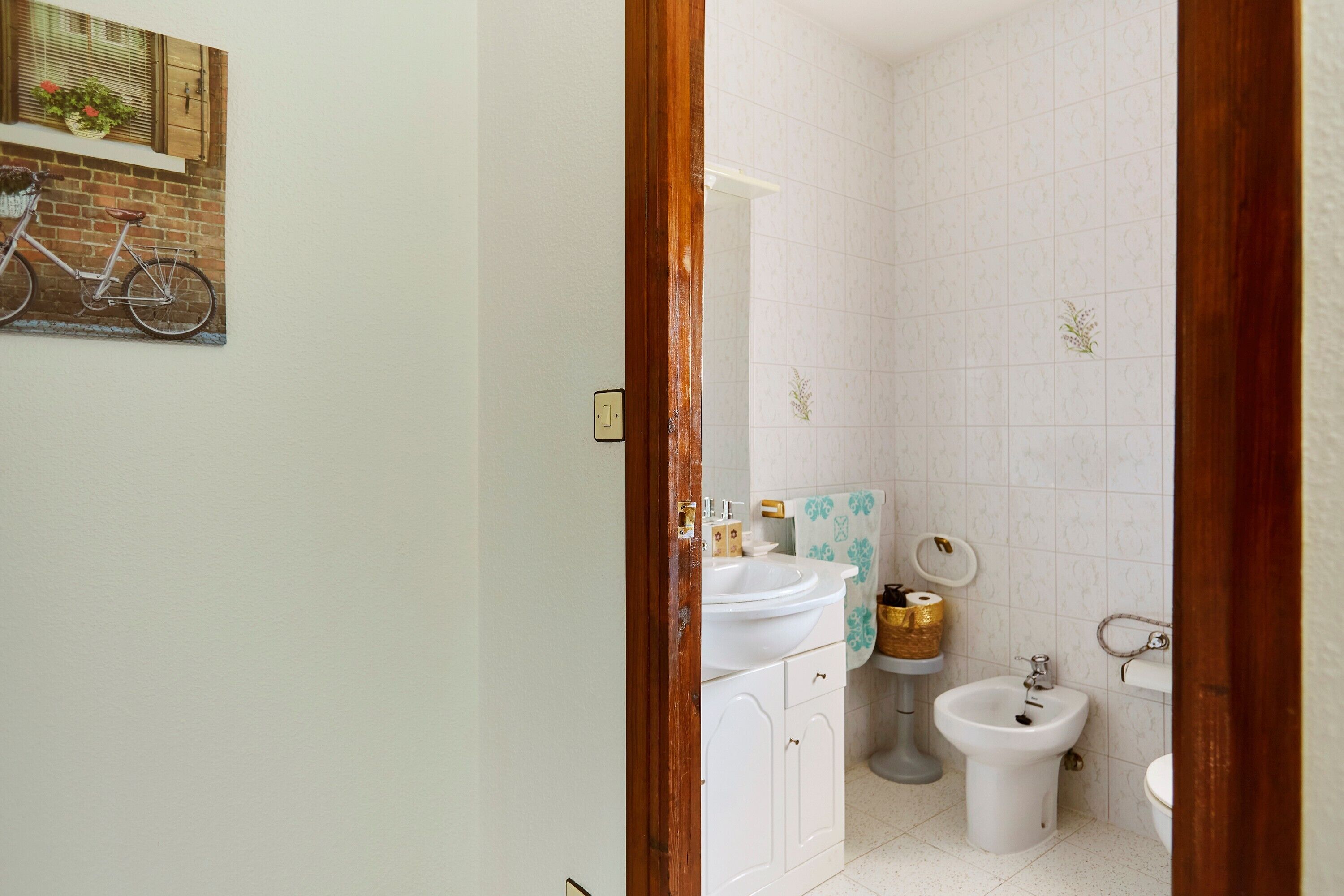 Un baño con lavamanos, bidé, inodoro y un marco de puerta de madera.