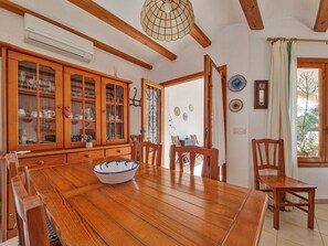 A dining area with a wooden table, chairs, and a cabinet with glass doors. - Holiday Home 'Isabel' with Sea View, Wi-Fi and Air Conditioning (Teulada)