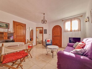 A living room with a purple sofa, wooden doors, a chandelier, and a small table. - Holiday Home 'Isabel' with Sea View, Wi-Fi and Air Conditioning (Teulada)