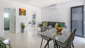 Ein modernes Wohnzimmer mit einem Glastisch, grauen Sofas und bunten Kissen.