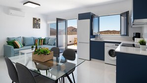 Un appartement moderne comprenant un coin repas, une cuisine et un balcon avec vue sur les montagnes.