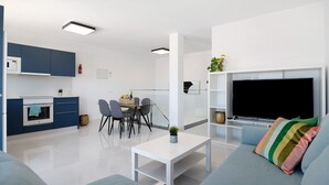 Un salon moderne doté d’un téléviseur à écran plat, d’un canapé, d’une table basse et d’un coin repas avec des chaises et une table.